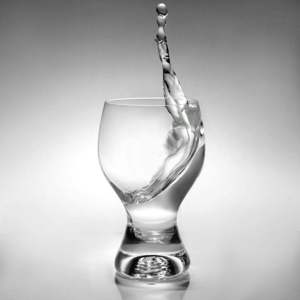 Artistic black and white shot of water splash in a glass, showcasing dynamic motion.